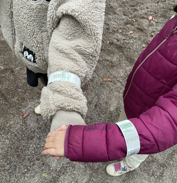 Två barnarmar med reflexband över sina jackor